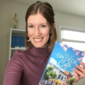 author leah dobrinska with her book entitled "love at on deck cafe"